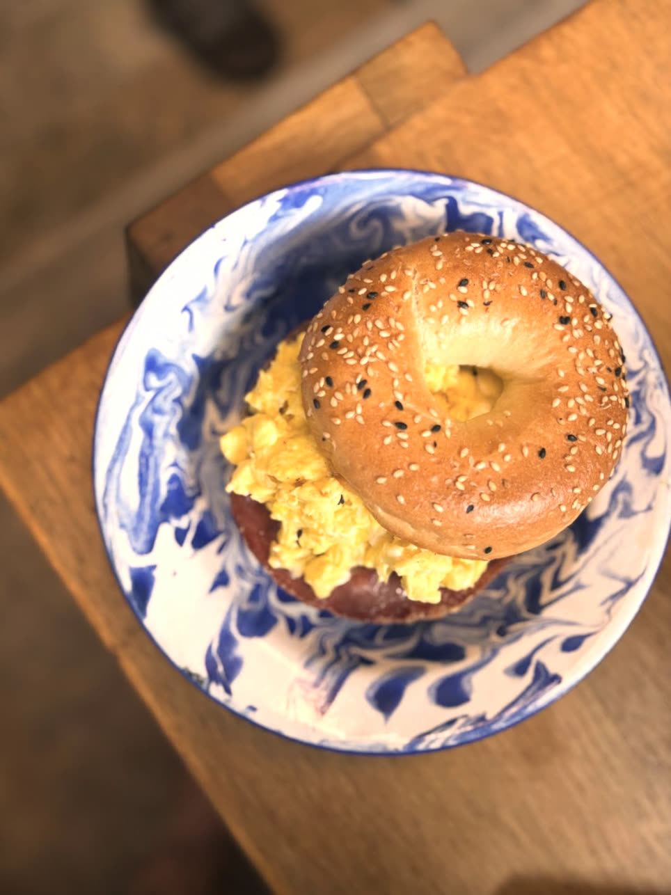 Bagel with scrambled egg in blue marble bowl
